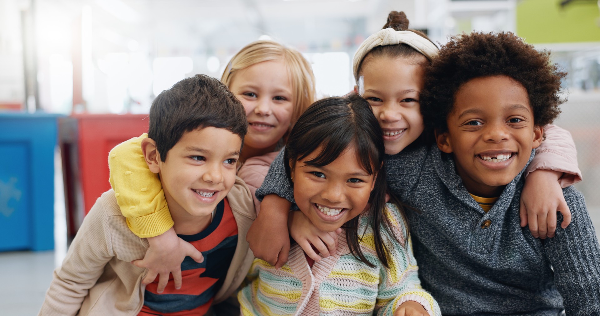 Ritratto, gruppo e bambini con sorriso a scuola per l'istruzione, l'apprendimento e la conoscenza con abbraccio. Studente, bambini o faccia a faccia con felicità in classe per lo studio, la borsa di studio o lo sviluppo dell'infanzia